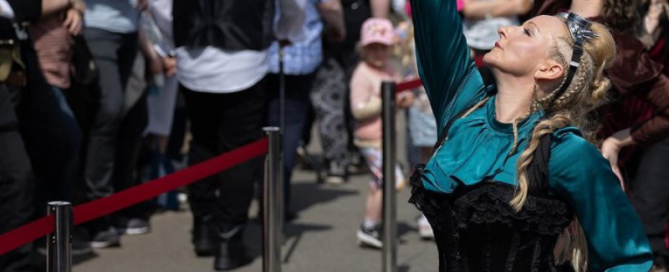 Image shows women dancing in the street in front of a crowd to promote Flourishing Culture Grants available for Ilfracombe and North Devon