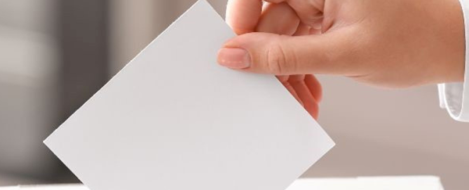 Image of a hand placing a voting slip into a ballot box to illustrate Ilfracombe Town Council General Election Guide