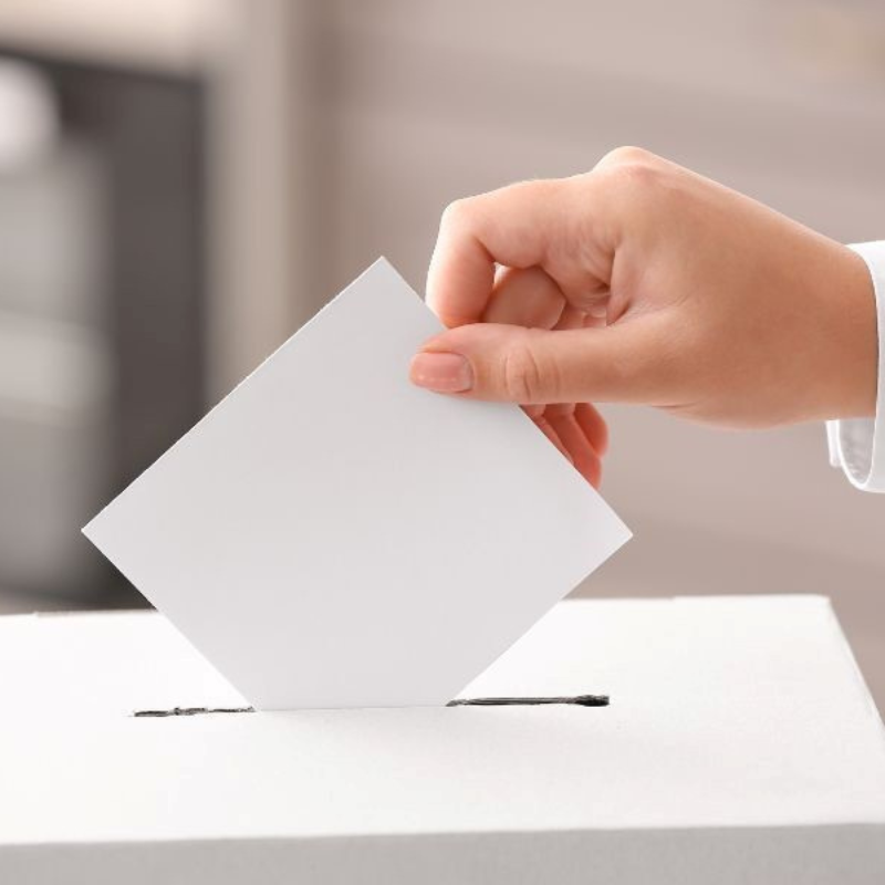 Image of a hand placing a voting slip into a ballot box to illustrate Ilfracombe Town Council General Election Guide